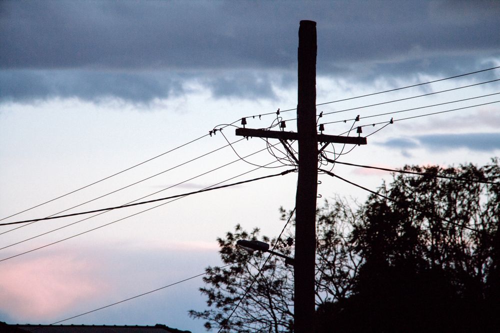 Power Lines And Utility Pole Silhouetted Against A Soft Pink And Blue Evening Sky