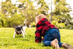 baby boy playing with a little dog in a park
