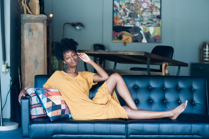 Woman sitting on couch smiling with eyes closed