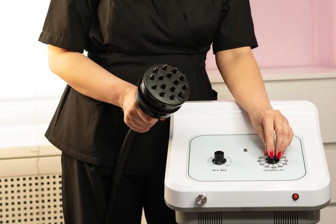 Spa professional adjusts settings on cavitation machine control panel