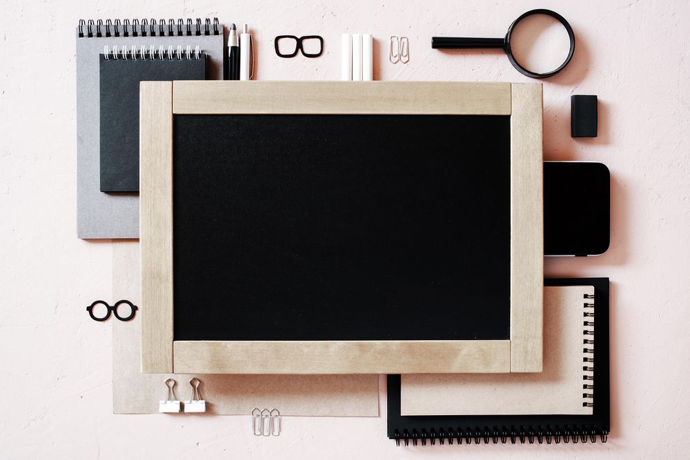 Top view of chalkboard and office supplies with copy space