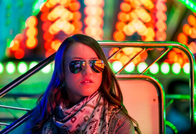 Smiling young woman near illuminated ferris wheel at night
