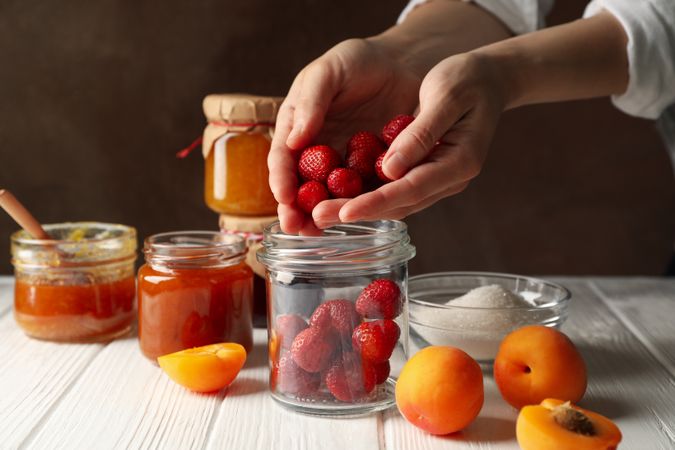 Woman puts strawberries in a jar. Preparing jam