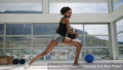 Black female doing stretching exercise with medicine ball bGR3Y2