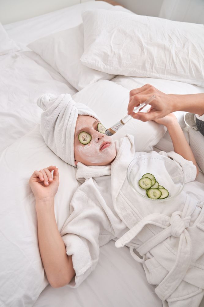 Unrecognizable woman applying facial mask on child