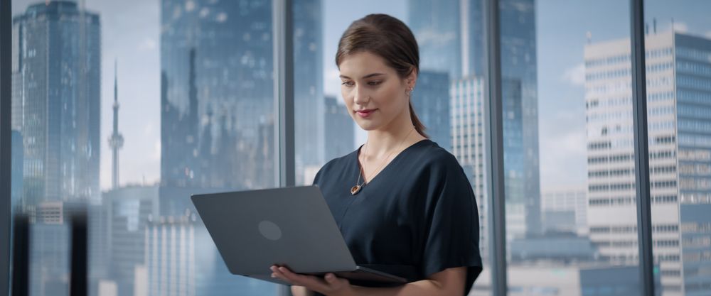 Portrait of Successful Businesswoman Working on Laptop Computer in Big City Corner Office.