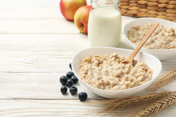Composition with oatmeal porridge on blank wooden background. Cooking breakfast