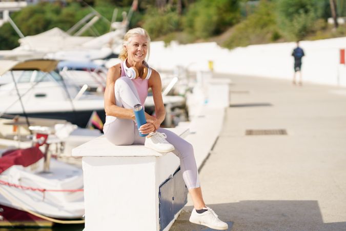 Mature female in fitness clothing drinking water from a metal water bottle