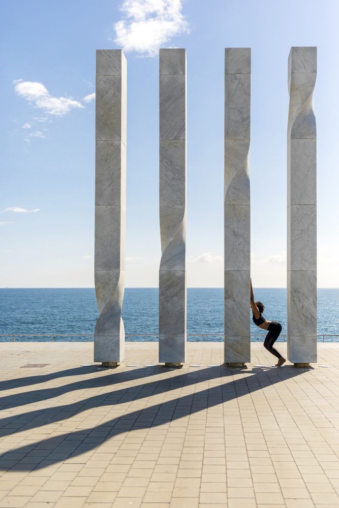 Side view of female stretching on sculpture by the ocean