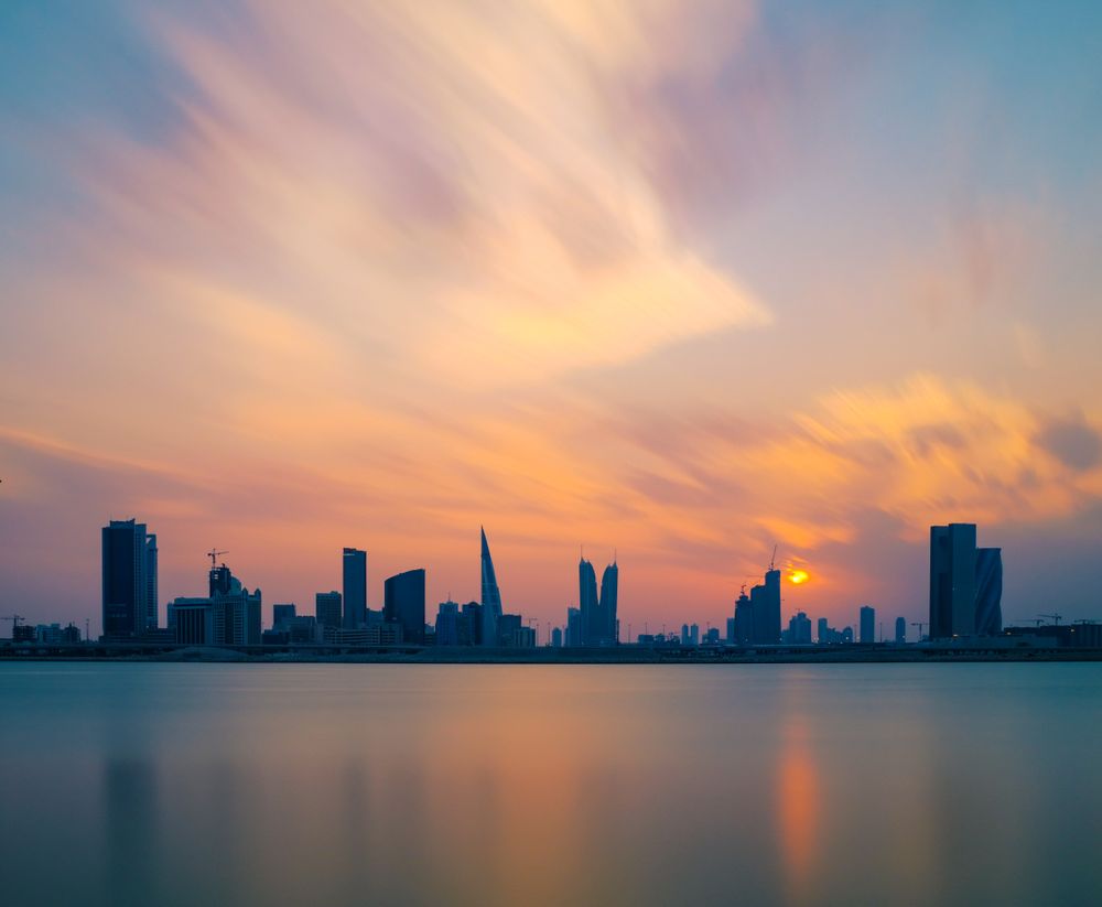 Silhouette of city buildings on next to a body of water during sunset