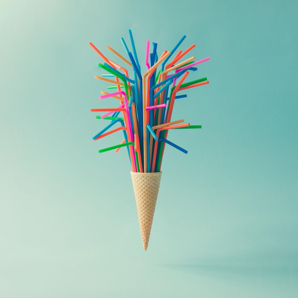 Ice cream cone with straws on light blue background