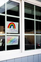 Two handmade signs taped inside of house window thanking delivery drivers and essential workers