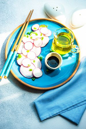 Top view of sliced radishes on blue plate served with chopsticks