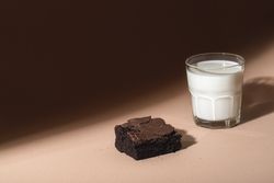 Glass of milk and brownie cookie in sunlight