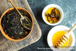 Fragrant loose leaf tea in bowl on counter with honey and dipper bDjVRp