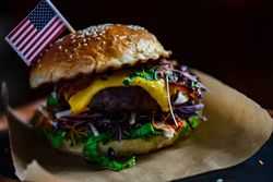 Bacon cheeseburger with melted cheese and vegetables on brown paper