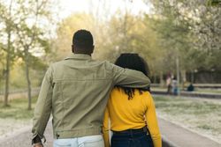 back view of a Black couple walking in a park
