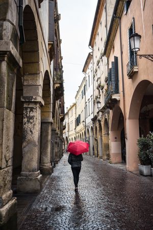 Tourist with umbrella walking at city street on rainy weather