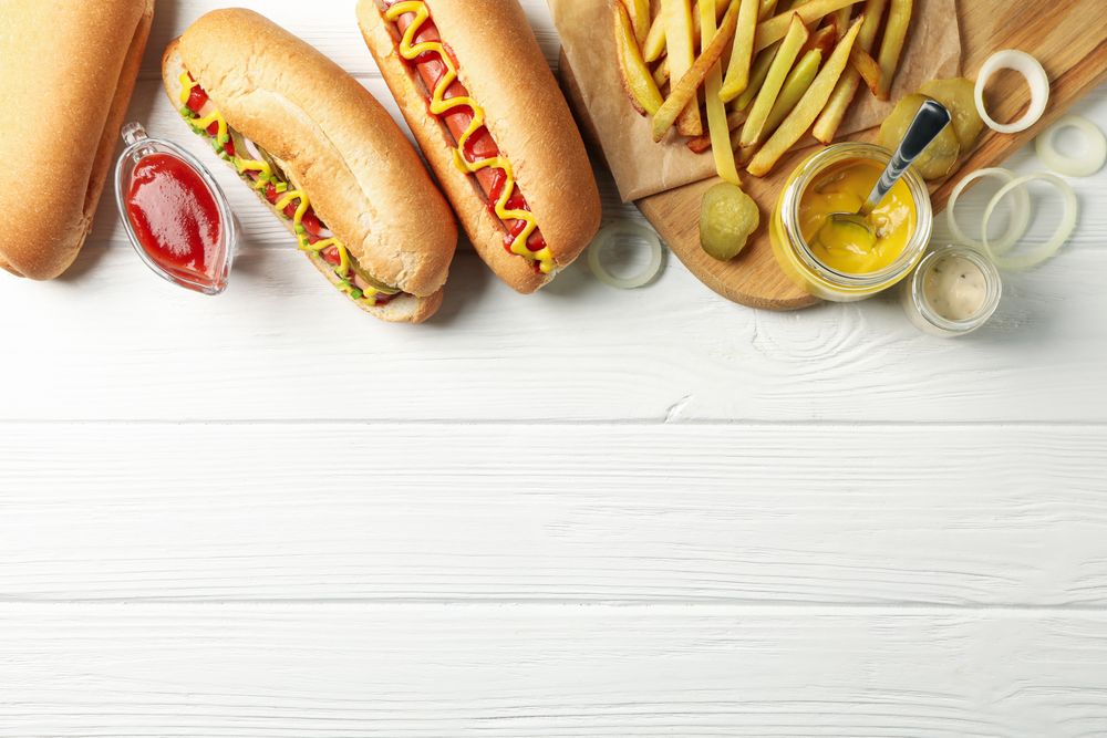 Hot dogs, fries potato and sauces on plain wooden background