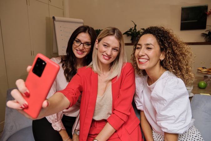 Smiling women taking selfie together on smartphone