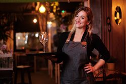 Cheerful waitress holding tray with wineglasses
