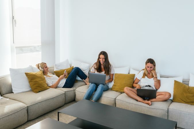 Women browsing gadgets on couch