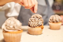 Faceless chef decorating cupcakes on table