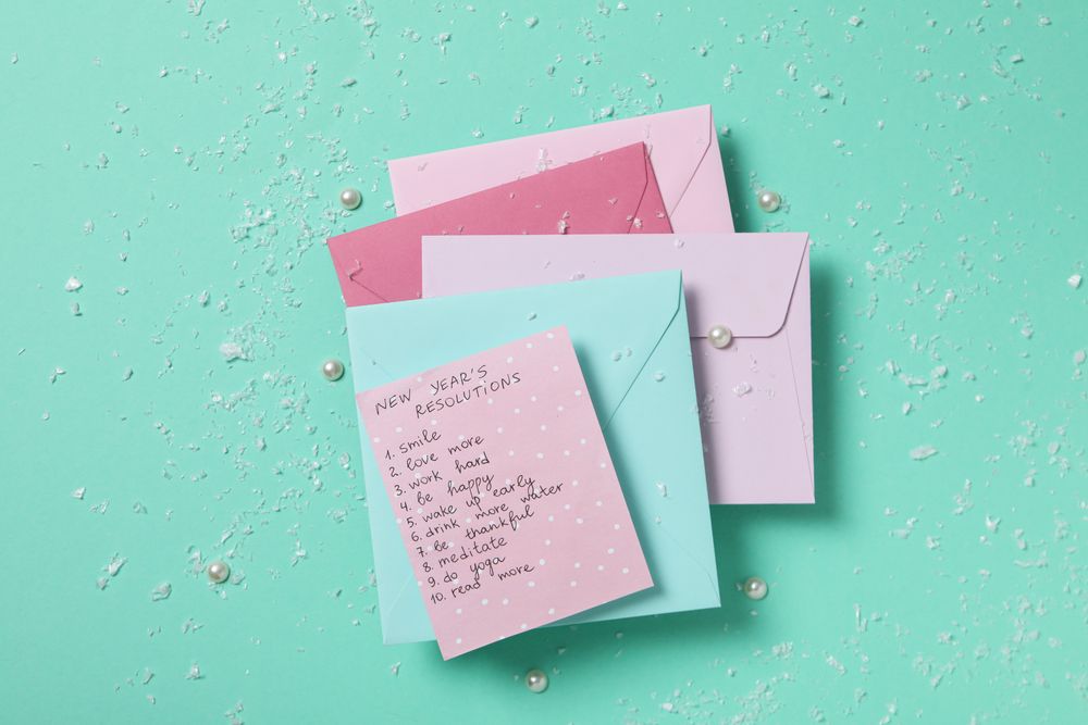 Envelopes and paper with list on green background, top view