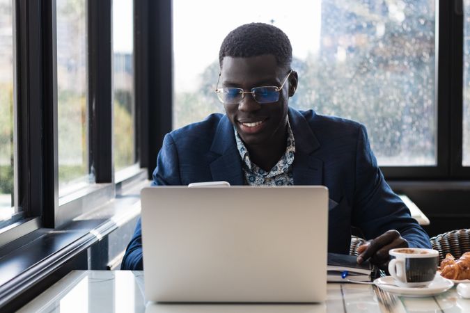 Stylish Black executive with smartphone and laptop in cafe