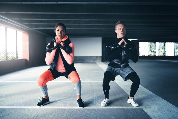 Two people doing squats with kettlebells