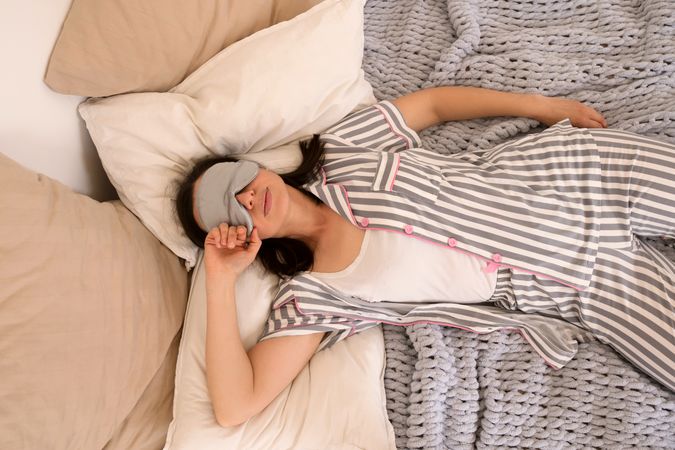 Woman sleeping peacefully in bed with eye mask.