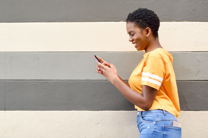 Laughing female checking phone in front of striped wall