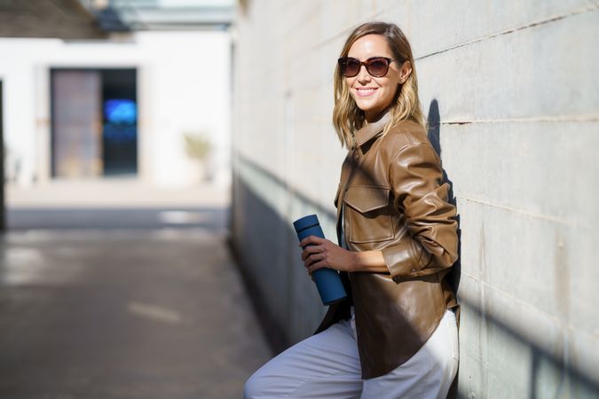 Cheerful stylish woman under sunlight with sunglasses and thermos