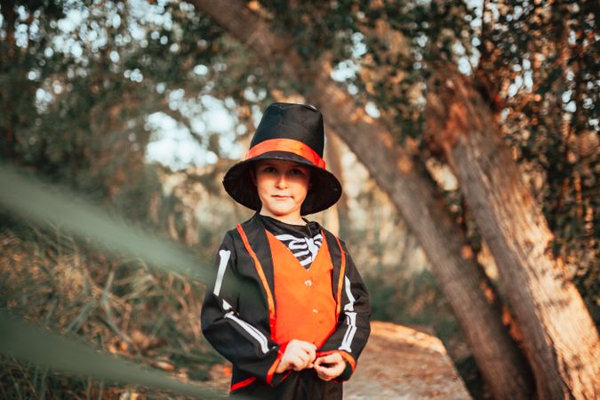 Boy in skeleton costume standing in the forest