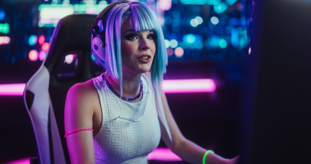 Smiling Cosplayer Talking to Her Online Friends on Desktop Computer While Sitting in Futuristic Cyberpunk Home.