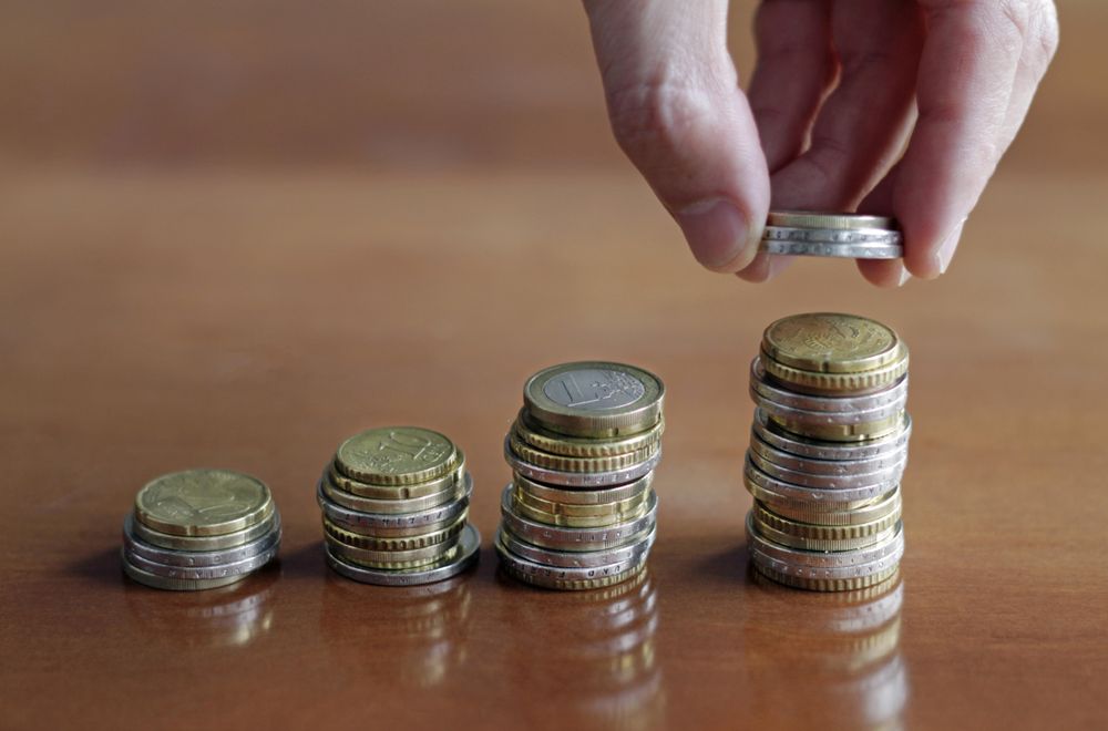 Person stacking coins on increasingly larger stacks