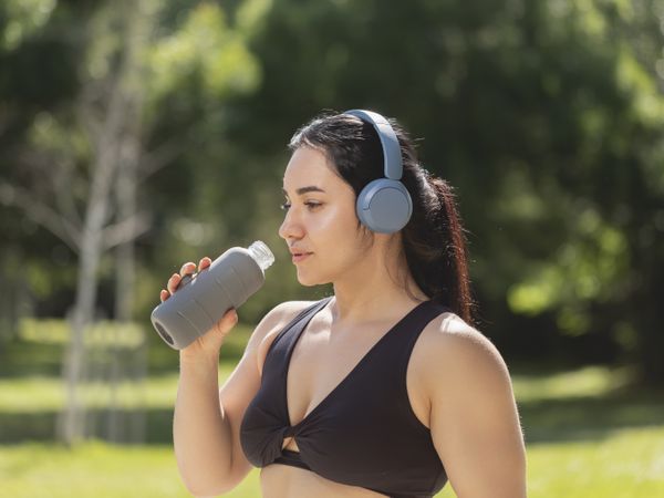 A young girl drinks water to hydrate herself, from a reusable bottle, during a morning exercise session