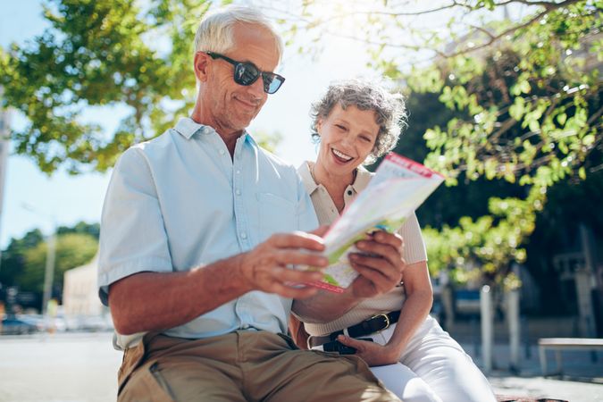 Older couple sitting outdoors in the city looking at a map