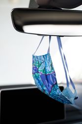Blue PPE mask hanging on car mirror