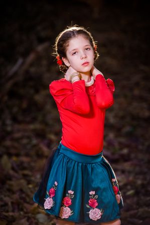 Young girl in red shirt holding her neck