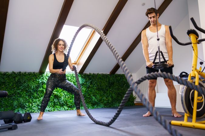 Couple doing rope exercise in home gym
