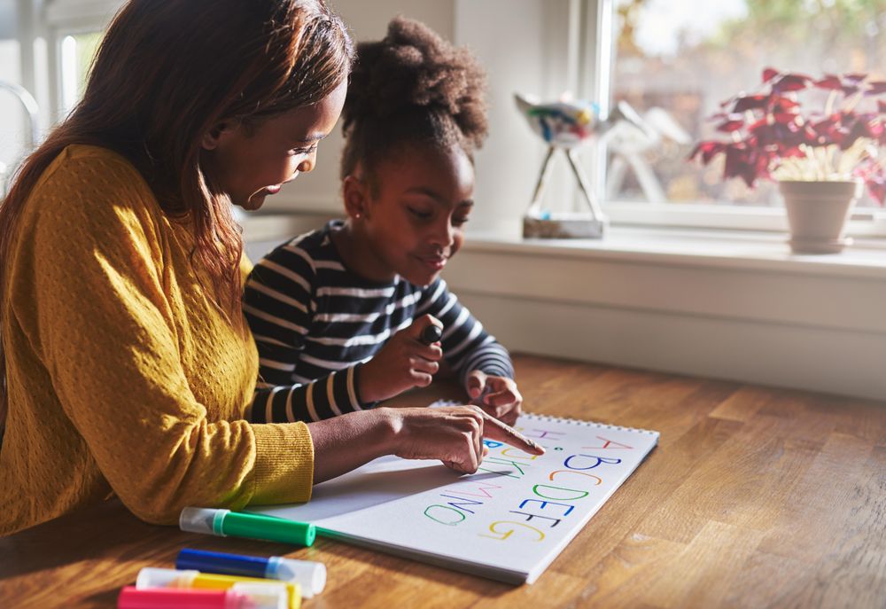 Mother helping daughter learn the alphabet