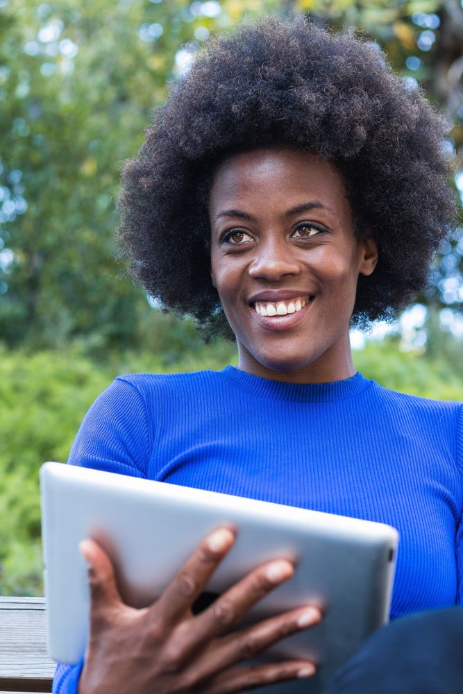 Smiling Black woman browsing tablet in city