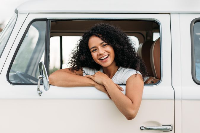 Smiling woman with brunette hair leaning out of a car window