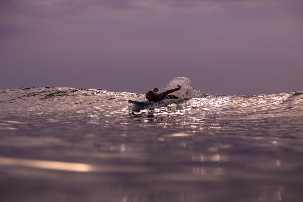 Man on surf board on waving water at sunset