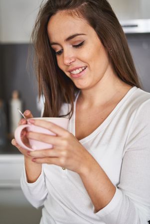 Woman drinking from cup in kitchen