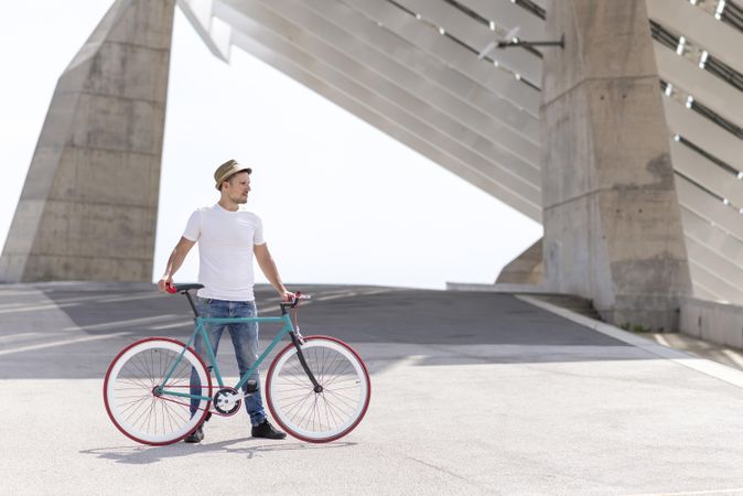 Male with bicycle standing under modern building