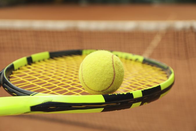 Tennis racquet with tennis ball against clay court