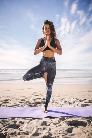 Beautiful woman at beach practicing yoga tree pose meditation