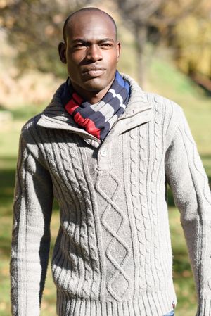 Serious male in woolen sweater walking tall in park